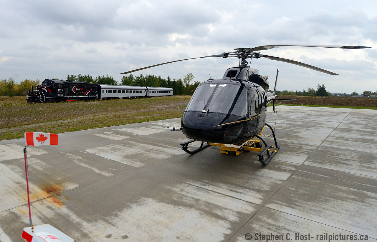Two modes of transportation meet in Snelgrove Ontario - but they are much much more closely linked than you think :) The helicopter is owned by Four Seasons Aviation Ltd. (http://www.fourseasonsaviation.com) and this facility seems to be fairly new. They are a charter airline (transportation, film, photography, etc) when I was on-site they had two pieces of equipment - this small helicopter and a much larger one inside their hangar. Give them a call if you have any aviation needs in the GTA :)
How are these two modes of transportation linked? Well think of it this way, those of us who are into Trains are also into other modes of transportation, and in some cases professionally. OBRY Engineer (and rp.ca contributor)  Steve Bradley is at the helm piloting CCGX 4015 north with about 150 passengers aboard, and he along with his Conductor Tyler would safely pilot their train through the beautiful scenery of the Credit Valley. Steve is a retired Air Canada pilot, having worked for them for 37 years and took up 'piloting' on the ground  with CP and later with Cando. We also have a few other flyboys on this site who contribute regularly. Regardless of what chair you sit in, or wether you are in the air or on the ground thank you to our 'pilots' for safely taking care of our transportation needs, your service is duly appreciated.
Photo notes: 1/100 chance to get the Canada flag sticking out like that. Mother nature was ANGRY and the wind gusts  were 80-100km/hour at that point. I will get a lottery ticket ASAP.