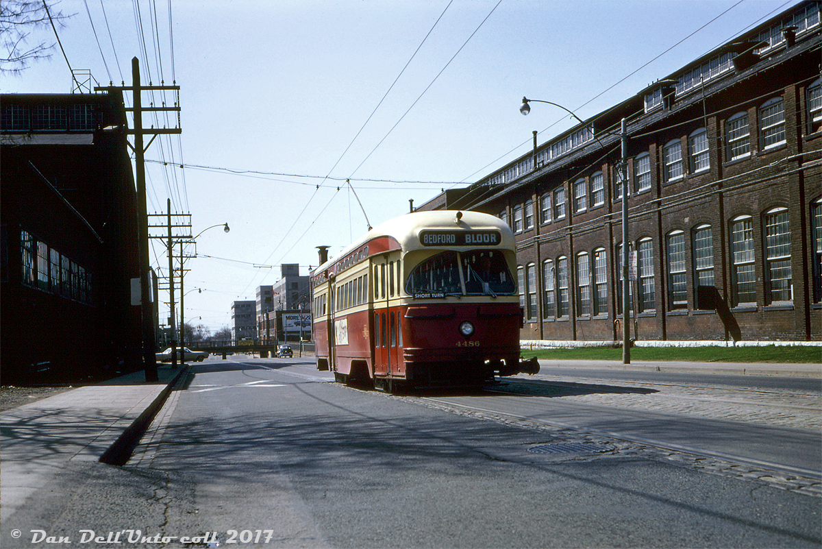 Amidst the industrial might of surrounding factory buildings, TTC PCC 4486 heads northbound on Lansdowne Avenue north of Dupont (and the CPR North Toronto Sub underpass in the background), operating on a Bloor run short-turning at Bedford Loop (on Bloor across from UofT's Varsity Stadium). Initially I thought this was an in-service deadhead, but a little more research and photo cross-checking suggests this may have been a weekend (Sunday) Bloor diversion due to trackwork, with Bloor cars diverting via Lansdowne, Davenport and Dovercourt.  Located a stone's throw from "The Junction" area, this stretch of Lansdowne Avenue was host to a number of factories and erecting plants, most prominently those belonging to Canadian General Electric (GE Canada) for manufacturing transformers and such, occupying vast amounts of real estate, employing many local residents, and served by rail with a number of sidings from the nearby CPR and CNR lines. One of CGE's Davenport Works long towering "headhouse" buildings is visible on the right. In the background south of the CPR underpass (with the car advertisement) is CGE's Royce Works plant (named after Royce Ave, now present-day Dupont St.). The tall grey buildings in the far background are American Standard (formerly Standard Sanitary - manufacturer of sanitary fixtures like sinks, toilets, etc). On the right are more CGE buildings, part of which is now GE-Hitachi's present-day uranium processing plant that's still in operation (much to the opposition of local activist residents).  As industry left the city over time, most of this has either been demolished or converted to condos and lofts. The rail sidings have been pulled up, as have the streetcar tracks: the opening of the Bloor-Danforth subway in 1966 nixed the Bloor streetcar and nixed Lansdowne carhouse as a streetcar base (converted for more trolleybuses later that year). The tracks on Lansdowne didn't last much longer, becoming home to another trolleybus route instead.  Robert D. McMann photo, Kodachrome from the Dan Dell'Unto collection.