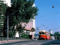 When Toronto was still debating whether to keep its streetcars or not in the 70's, a number of transit and rail photographers turned their cameras toward the Mount Pleasant streetcar line that faced an uncertain future, including Robert McMann. Seen here, TTC A-8 class PCC 4518 heads southbound on Mount Pleasant just below Merton, climbing the old CN Belt Line bridge and passing the landmark Dominion Coal and Wood silos, a month before streetcar abandonment on this route.<br><br>The Mount Pleasant streetcar service had begun in 1925 as part of the St. Clair streetcar route, until it became its own route in 1975 from St. Clair subway station to Eglinton Loop at Eglinton & Mount Pleasant (note the southbound car is incorrectly signed up for destination Eglinton, when it should read St. Clair). This aging bridge in the photo was the catalyst for discontinuance: it needed replacement, and that combined with track rehabilitation costs of the line opened up the can of worms to keep Mount Pleasant as a streetcar line or convert it to cheaper trolley or diesel buses. After changing decisions once or twice due to pressure from local residents, and the Metro Roads department, it was announced in July 1976 as a bit of a surprise that streetcar service was to be discontinued that month (all this after it had been announced in April the route would be kept and rehabilitation work made the next year). The last full day of service on Mount Pleasant was July 25th 1976, which included a Peter Witt charter run early that morning.<br><br>As for the CN Belt Line rail spur (originally built as the Toronto Beltline Railway in the 1890's, then used by Grand Trunk and later CN for serving local industries), the line extended east from the CN Newmarket Sub at Fairbank to serve a number of local customers along the way such as Fairbank Lumber, the TTC's Davisville Yard (new subway deliveries), and Dominion Coal & Wood, and ended just east of the bridge pictured (the siding for the silos here was a westward facing switch on the east side of the bridge). This eastern portion of the line through Forest Hill and to Mount Pleasant was likely doomed by low traffic and the new Spadina Expressway construction that would sever it around Mile 1.66 by Marlee Avenue. CN lifted the rails starting in April 1970 (it had apparently last seen service east of  Mile 1.66 in 1969), and the raised berm the line occupied across the Spadina Expressway "pit" was eventually removed by 1975 (visible <a href=http://jpeg2000.eloquent-systems.com/toronto.html?image=ser12/s0012_fl1970_it0113.jp2><b>here</b></a>, although the Expressway would not be complete for a number of years). The city acquired the right-of-way in 1972 for park or trail use (eventually becoming the present day Kay Gardiner Beltline trail, including the western portion of the line that lasted until its own abandonment in 1988). The Dominion silos lasted until 2001 before being demolished for condos.<br><br>TTC 4518 was a little luckier: rebuilt as A-15 class car 4615 for Harbourfront line service in 1985, it currently resides at the Kenosha Streetcar Society in Wisconsin, with 5 other ex-TTC cars.<br><br><i>Robert D. McMann photo, Kodachrome from the Dan Dell'Unto collection.</i><br><br><i><u>References for further reading:</u><br><a href=http://www.bytownrailwaysociety.ca/phocadownload/branchline/2001/2001-07-08.pdf><b>Branchline magazine, July-August 2001 (25th Anniversary, TTC Mount Pleasant Carline Abandonment).</b></a><br><a href=https://transit.toronto.on.ca/streetcar/4114.shtml><b>Transit Toronto - The Mount Pleasant Streetcar (deceased).</b></a></i>