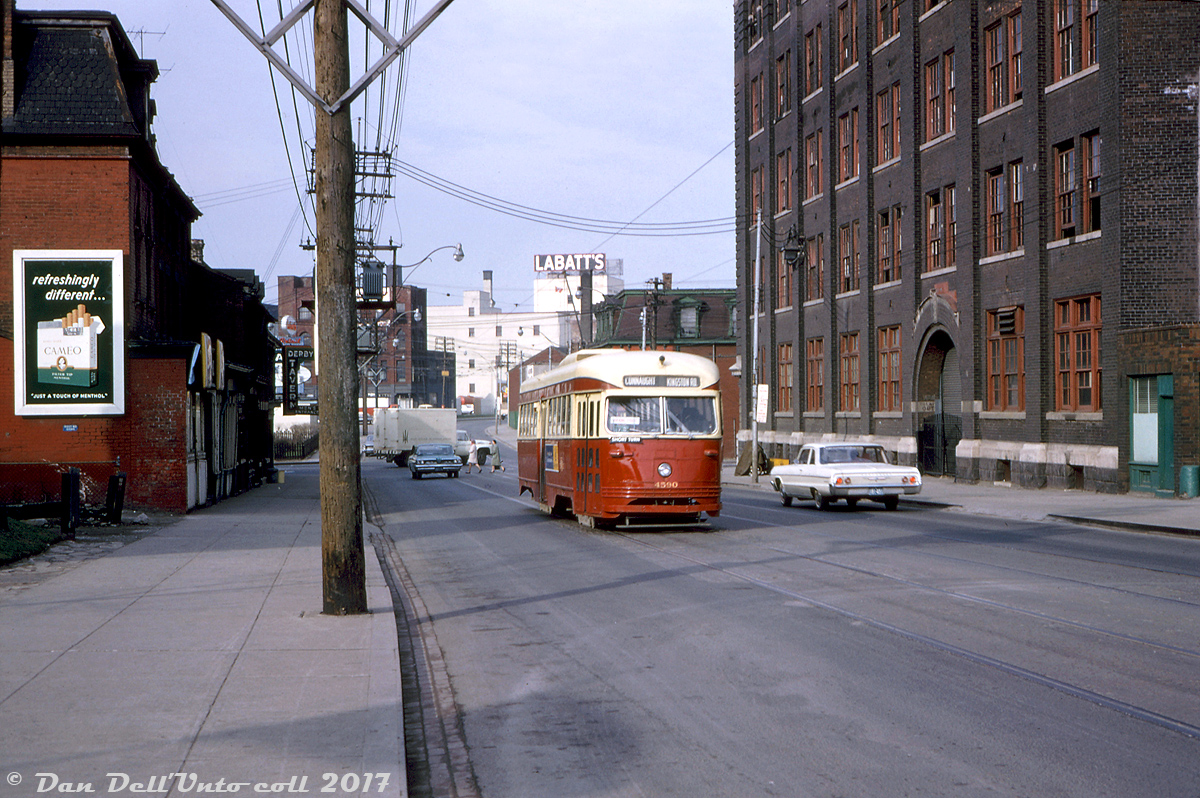 TTC PCC 4590, operating on a Kingston Road rush hour "tripper" short turning at Connaught (probably a morning carhouse return trip to Russell Carhouse), heads east on King Street East at Power Street. Note the white and orange "via King Street" route sign in the windshield, signalling this Kington Road car would be diverting down King St. for its west-end routing (rather than the alternate Kingston routing of Queen St. to McCaul). 

This area of King Street (Corktown) boarders on the industrial "West Donlands" area to the south, with many old manufacturing buildings and factories visible such as the Labatt's Brewery in the background along King near Berkeley. Looking back on other photos of the area, there's a very working-class feel to this stretch of King Street in the 60's. Also note the Derby Tavern, located at the corner of King & Parliament. If one looks closely, they can see the "Men's Entrance" sign. The "Ladies and Escorts" entrance was off Parliament St., leading to a separate drinking area. As far as I can determine, this all originated from old backward-seeming (at least today) Ontario Liquor Board laws that came into effect in the 1930's requiring separate drinking areas - one for just men, and one for women and women with their husbands. Backwards logic with the war, spread of disease, and I suppose what could be termed today as "hookup culture" between singles (more information about all that here and here for those wondering).

4590 was part of the A-10 class group of "pre-war" PCC's originally built for the Cincinnati Street Railway in 1940 and acquired by the TTC in 1950 (the Cinci cars were part of the first of many acquisitions of used PCC's to help build the fleet - in part due to the increasing costs of new cars, other transit agencies selling their streetcar fleets in favour of buses, and to replace some of the old wooden streetcars the TTC was still running). The secondhand and used cars tended to leave the fleet before the ones acquired new, and the A-10 class was eventually all retired, disposed of or sold off in the mid-70's, leaving many younger and newer PCC's still in service.

John F. Bromley photo, Kodachrome from the Dan Dell'Unto collection.