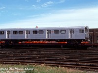 Built new for the Toronto Transit Commission in the mid-70's by Hawker Siddeley Canada in Thunder Bay, brand new TTC "H5" subway car 5741 sits on a NIFX 1000-series flatcar at Canadian Pacific's Parkdale Yard, awaiting interchange to CN and final delivery in east end Toronto to the TTC's Greenwood Yard via spur track. Note the red farm equipment on flatcars behind, from the nearby Massey Ferguson factories in the industrial Liberty Village part of town (since gentrified greatly with condos and lofts).<br><br>The 138-car group of H5's was just the latest iteration of the basic RT-75 75' long aluminum bodied subway car design introduced by MLW in the early 60's as the M1, and followed by HSC's H1, H2, H3 & H4. Changes included smooth end top cap pieces by the top lights (instead of profiled like on the H1-H4), "Chopper Control" (for stepless acceleration and regenerative braking) and were the first cars to feature air conditioning on the system. The H5's were also initially delivered with "blackface" black ends, but were eventually all repainted silver. Known by passengers for their yellow doors, whining noise when accelerating or braking (from the chopper control), and musty air conditioning condenser smell, the H5's were phased out by the new Bombardier Toronto Rocket trains starting in the early 2010's, and the final train of H5's made its last run on the Yonge-University-Spadina line in June of 2013. Most were supposed to be refurbished for use on a Lagos light rail project in Nigeria, and many were shipped to New York for refurbishing, but the plan fell through (new rolling stock was later purchased) and the H5's were cut up for scrap. Apparently some Canadian enthusiasts were able to contact the scrapper in the US, and obtained a U-haul load stash of H5 goodies, but that's another story...<br><br>For the rail enthusiast, the eclectic mix of rolling stock used to ship subway equipment varied over the years, from standard CP flatcars used to deliver the original 57' long "Red Rocket" Gloucester cars in the 50's, specially built CP 6-axle flatcars made from cut down heavyweight passenger cars, to these NIFX 1000-series 4-axle flatcars equipped with pedestal supports (originally lettered "North American Car Corporation", some painted out to leave "Can Car", presumably leased to HSC/Can-Car in Thunder Bay), to yellow 89' TTX flats used to ship the H6's. The last subway deliveries by rail were the T1's to Greenwood in the 90's, and all subway cars in and out of the system are presently moved by truck and special low-loader flatbed trailer.<br><br><i>Robert D. McMann photo, Kodachrome from the Dan Dell'Unto collection.</i>
