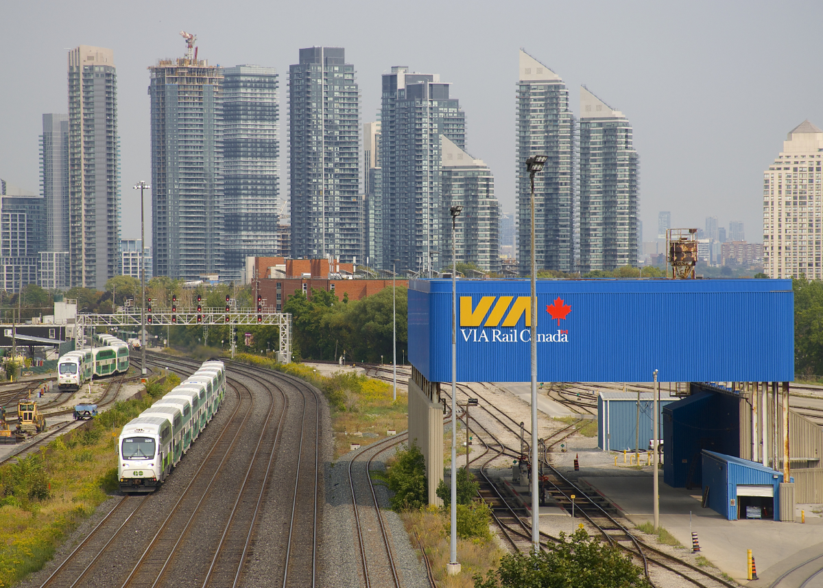 Cab car GOT 326 leads a westbound past GO Transit's Willowbrook maintenance facility at left (where a train is seen entering the yard) and VIA Rail's Toronto Maintenance Centre at right.