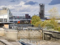 As happens every fall, the Lachine Canal has been mostly drained, as CN 7228 stops on a bridge over the canal. Soon it will back up towards Bickerdike Pier with a cut of grain cars.