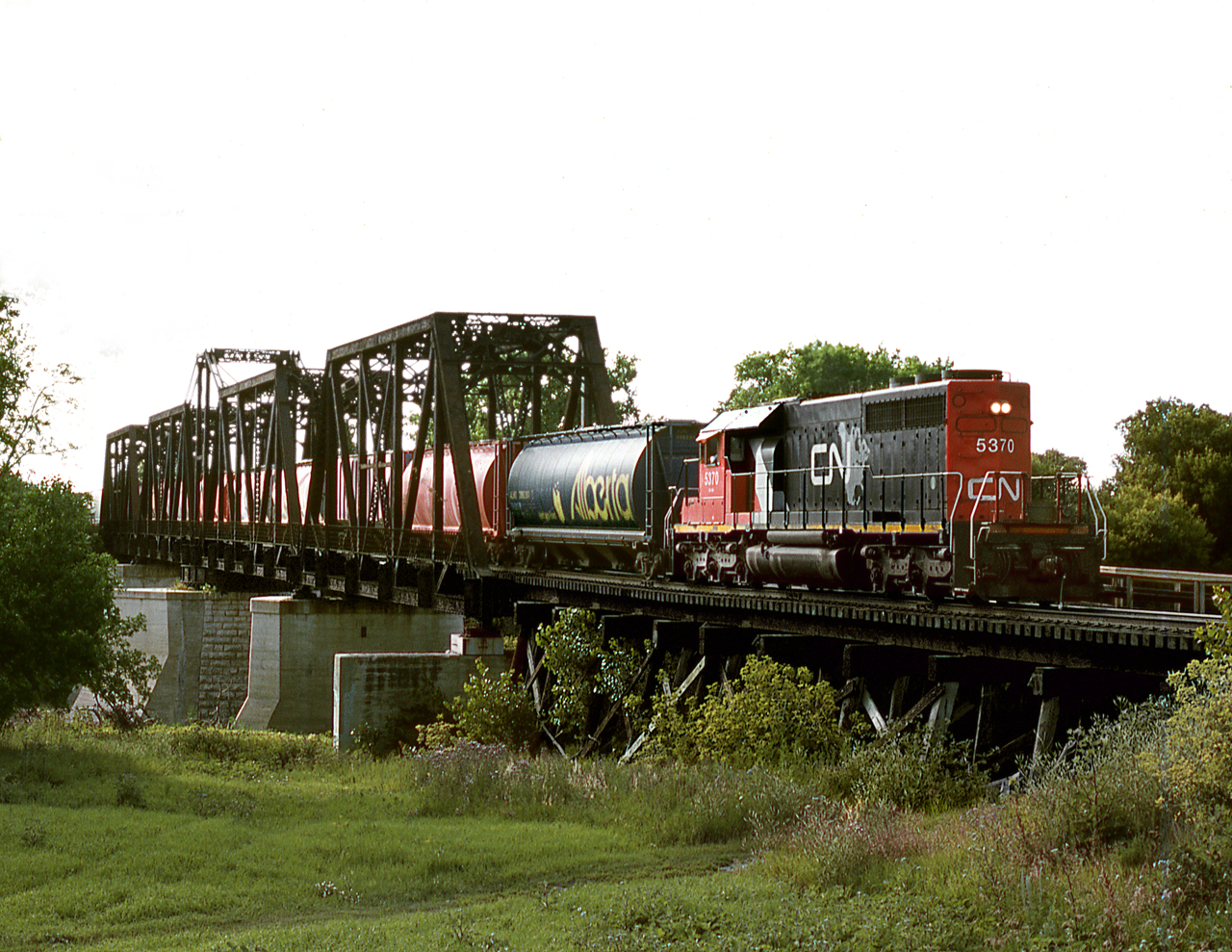 CN's Emerson wayfreight out of Winnipeg crosses the Red River at Emerson after turning on the wye on west side of river,Former NP junction. It will pick up cars off the BNSF(Former GN) including haulage cars for BNSF's yard at Winnipeg. The train operated in 2003 as a daily daylight turn