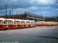 Lined up and ready to be dispatched for evening rush hour duties, TTC 4441 and a bunch of her sister PCC cars crowd the yard tracks outside Lansdowne Carhouse under cloudy afternoon skies in August of 1955. The route display rollsigns (front, right side) on the closest cars show Carlton for their last assignment, while the destination rollsigns (front, left side) say Lansdowne, for when they short turned and headed back to the carhouse at the end of morning service. Note some still have the front silver headlight ring that was being removed from all of the cars.<br><br>Eventually peaking at a total of 745 new and secondhand cars, by this time in the 50's Toronto's PCC streetcar fleet was the largest in North America (and by extension, the world). The opening of the Bloor-Danforth subway and its extensions in the mid-late 60's saw many of the older cars retired and disposed of, and some secondhand cars were sold off in the 70's to other transit agencies. The bulk of the PCC fleet were phased out in the 80's by new CLRV and ALRV streetcars, with a select few rebuilt and living on in harbourfront service before being retired and sold off in the late 90's. Two PCC streetcars, 4500 & 4549, were kept and are used on occasion for special event and charter service.<br><br>Original photographer unknown (Al Chione duplicate slide), from the Dan Dell'Unto collection.