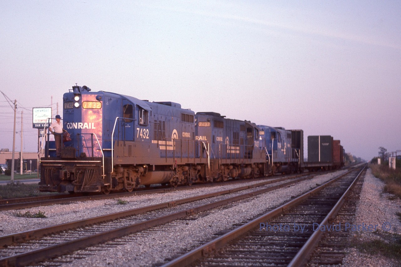 Three Canada Division GP9s (7432-7437-7434) lead a small WQST-1 off Westbound main and into the Class Yard lead at Howard Ave, Windsor Ont just before sunset on Sept 30th 1992. Normally, this train would arrive in Windsor early afternoon and would be back in St Thomas by this time. In the distance above the Eastbound main can be seen the signals at Pelton.