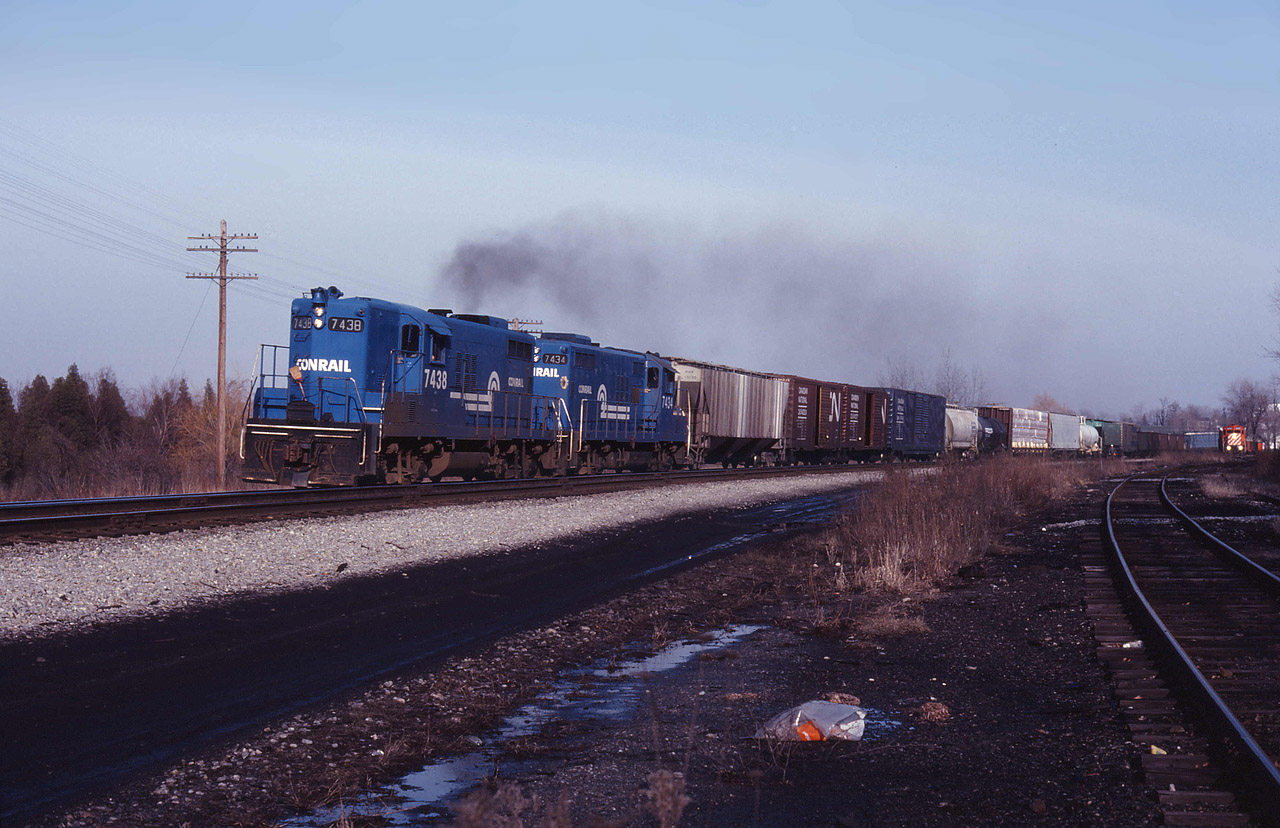 With the steel train rounding the wye off the TH&B, Conrail local is charging eastbound out of Waterford with a pair of Canadian geeps for motive power. (Corrections welcome please).