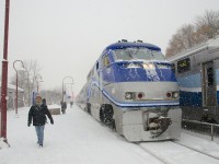 AMT 18 is about to stop at Montreal West station as the snow falls during the morning rush hour. At right a deadhead move heads west.
