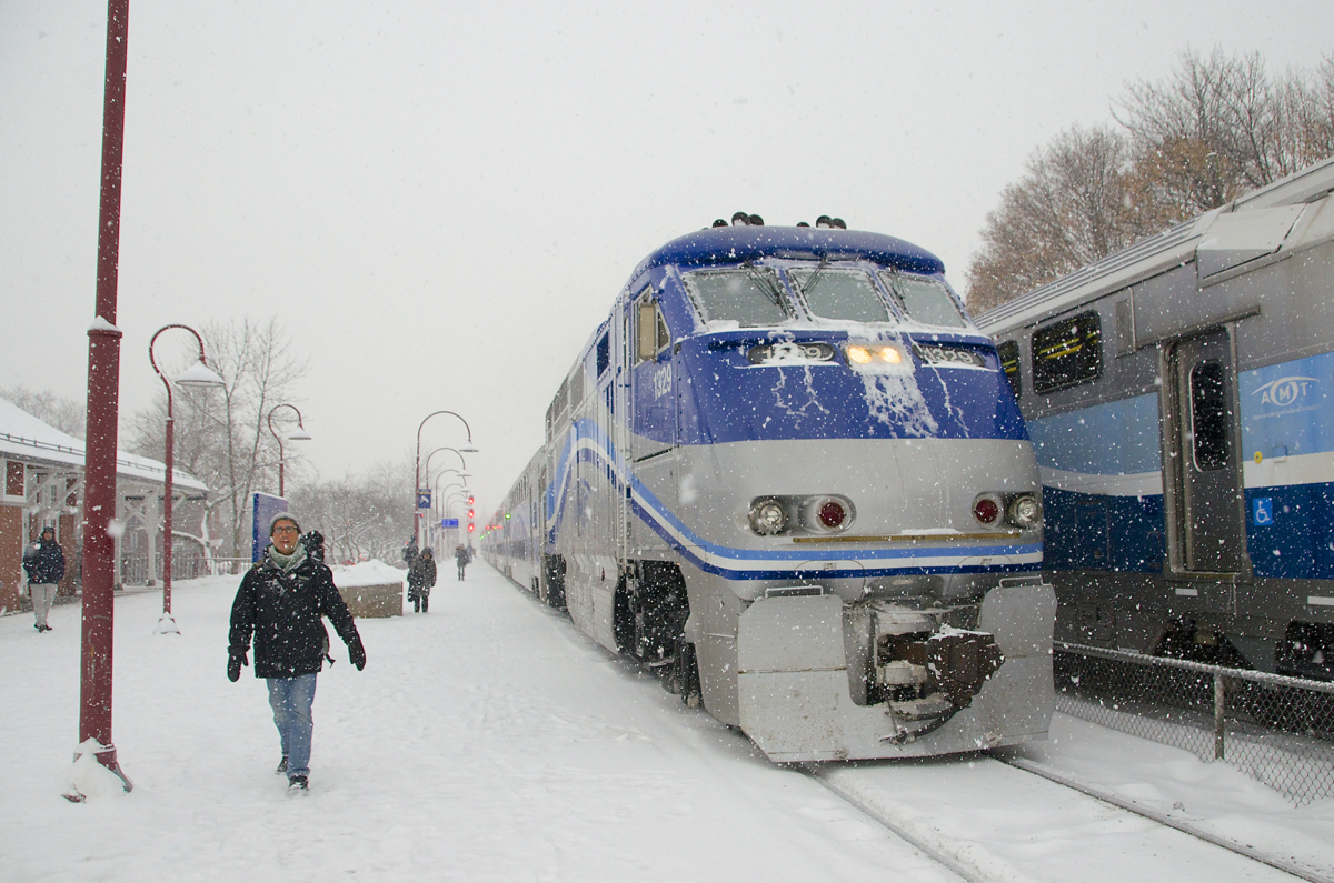 AMT 18 is about to stop at Montreal West station as the snow falls during the morning rush hour. At right a deadhead move heads west.