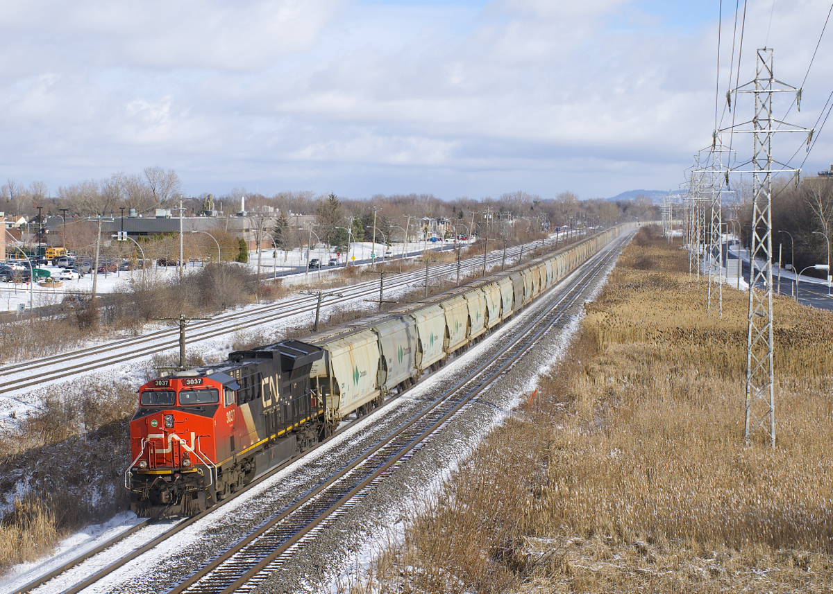 CN 3037 brings up the rear of potash train CN B730 as it kicks up the snow by MP 14 of the Kingston Sub during a brief period of sunshine. This 204-car train has CN 2949 and CN 3091 up front and CN 2937 139 cars from the front and is destined for Saint John, NB