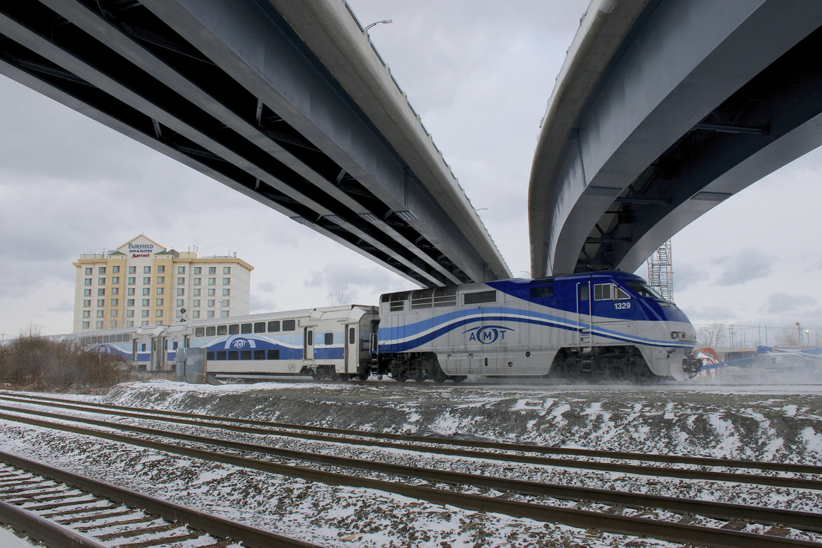 Finally completed. AMT 1329 is pushing AMT 61 towards its next stop at Dorval as it kicks up the snow. The train is passing under a set of overpasses that link Autoroute 20 with the Montreal-Trudeau airport and that were delayed for a number of years due to the government of Quebec failing to get permission from CN and CP to cross their right of ways here.