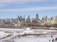 The <i>Adirondack</i> is leaving Montreal with AMTK 100 leading five Amfleet cars, behind the train is the skyline of downtown Montreal.
