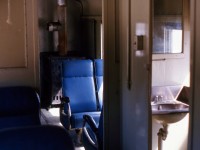 SPARTAN BUT SPECTACULAR. The sunlight reflects from what remains of the previous winter's snow through the windows of Terra Transport Coach 757 to illuminate its spartan but comfortable interior at the flag stop of Quarry. Originally built in 1943 as coach No. 40 for the Newfoundland Railway by the CC&F it was assigned to the Bishops Falls - Corner Brook run from 1984 to 1988 after the mixed runs on the branchlines were cancelled. Were it not for the excitement of the photographers and his girlfriends first run on a Newfoundland train, the radiant heat from the oil stoves (one in each end and tended to by the conductor) and the huge comfortable vinyl seats, it would be so easy to drift off to sleep with the gentle rocking and rolling of the narrow gauge train.