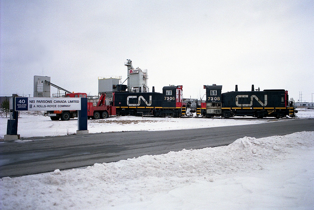 While switching cars at the NEI Parsons Company (engineering firm owned back then by Rolls Royce) the front truck of CN 7306 went on the ground, and assistance had to be called in. In the days of fixed lenses it was hard to line up this shot; I was unable to back up far enough to get a clear picture of everything I wanted to, and preferred to get the location in the shot. Neilson Av is a short street between Welland Av and the North Service Rd in the city, and it was about the only industry left to be service by rail north of the QEW by this time.