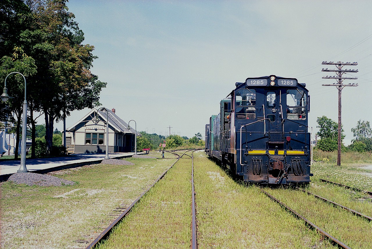 Railink 1285 (x-CANAC, xx-CN same number)idles on what is left of the old Dunmnville sub (lifted 1985) with a short cut of cars. The renovated CN Caledonia station can be seen on the left. Perhaps the lads have gone for a lunch break, after all they are a hop, skip and jump from a local Timmies. Evidence of a hot and dry mid summer can be seen in the form of some struggling grasses on the RoW. Not easy growing area in the best conditions.