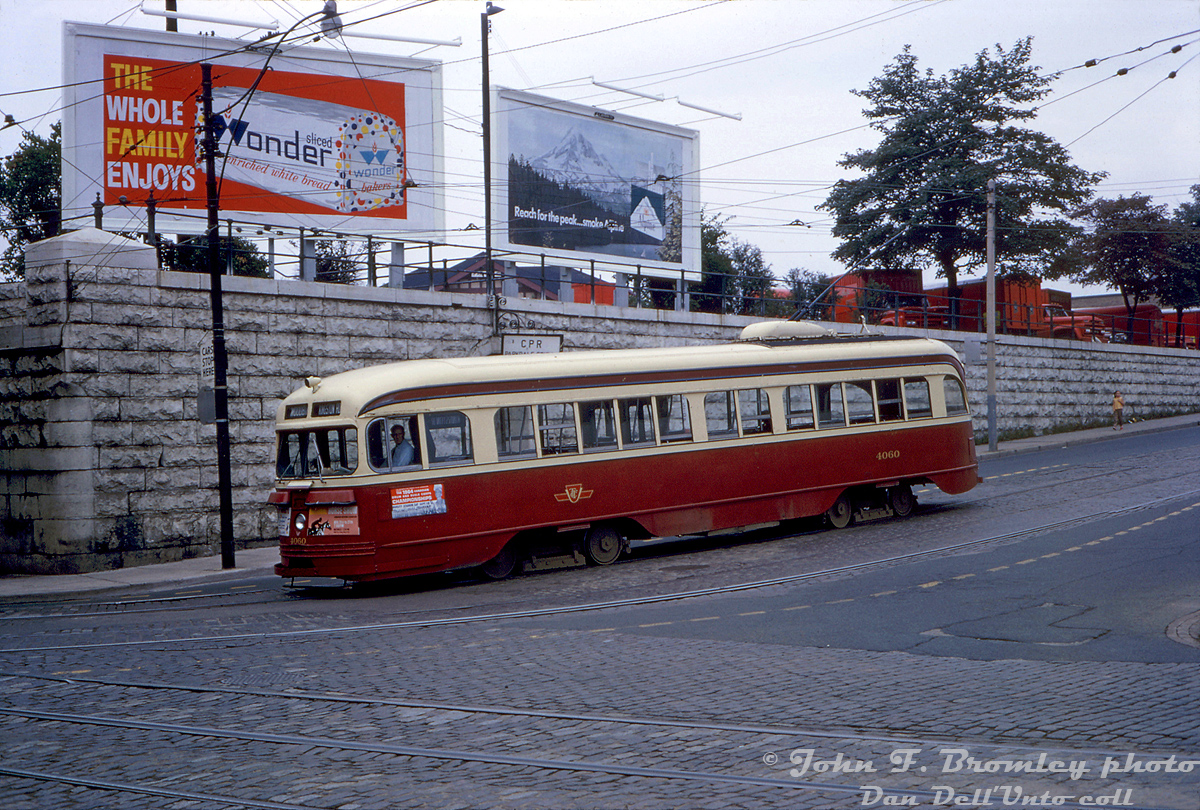 TTC A1-class air-electric PCC 4060 curves east from northbound on Dufferin Street to eastbound on Queen Street West, working a Kingston Road car to Woodbine Loop in the Parkdale area of Toronto on August 22nd 1964. The sign behind the streetcar says "CPR Parkdale Station", above an arch cut into the stone retaining wall and stairway that lead up to CP's Parkdale Station, the top of which is visible (closed a few years later in 1968 and later demolished). The red trucks lining the top of the retaining wall are for Canadian Pacific Express, who had their building next to the station.

Advertisements on the streetcar include ads for the 1964 Canadian Drum & Bugle Corps Championships, a horse show, and a partially obscured one for a Mickey Mouse performance at the Hummingbird Centre (only 50 cents!), plus billboard advertisements for Wonderbread white bread (some things never change), and Alpine Cigarettes.

John F. Bromley photo, Dan Dell'Unto collection.