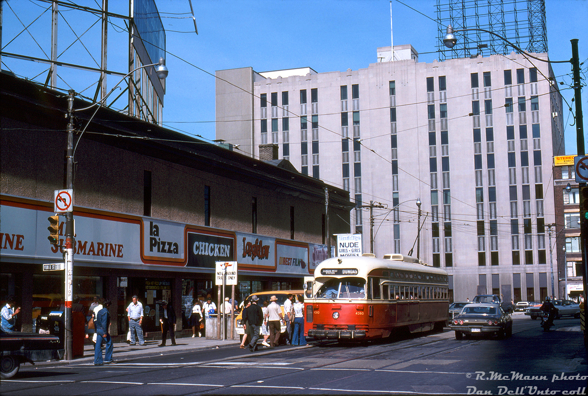 TTC PCC 4380 operating on the Dundas route (pre-route numbers, which started around 1980) stops to pick up passengers at the north-east corner of Yonge and Dundas, by a set of stairs that lead down to the Dundas Subway Station on the Yonge line. The low-rise building at the north-east corner, once home to the Brown Derby Tavern, has recently been remodeled in the past year or two with various fast food and retail outlets (and Paradise Nude Girls, from a time when Yonge St. was the place to go in Toronto to get your smut). 

Much has changed here in roughly 40 years: the PCC streetcars have been replaced with CLRV's (soon to be replaced with new Bombardier equipment), the low-rise commercial building on the corner has been replaced with the towering 10 Dundas East (ex-Metropolis) building plastered with advertising, and with an indoor subway connection. Ryerson University's Victoria Building in the background is probably the only recognizable thing today. Oh, and much of the smut has since been gentrified from Yonge Street (the holdout being the Zanzibar up the street).

Robert D. McMann photo, Dan Dell'Unto collection.