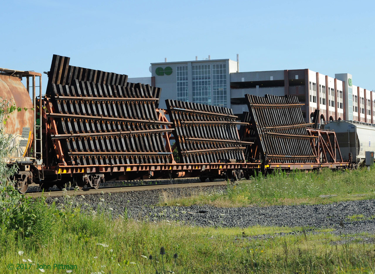 An interesting load of new pre-fabricated diverging track sections on a pair of CN MoW cars arriving on the afternoon inter-yard transfer from Aldershot to Oakville Yard.  Photographed just east of Oakville GO/VIA station; the multilevel parking garage looms in the background.