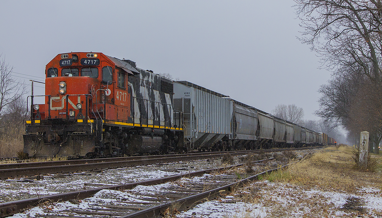 Before the winter's first snowfall, dilapidated looking CN 4717 (still in Zebra stripes) pulls an unusually long string of cars on 514 into the siding of the former CSX yard. It is nudging it's nose just beyond one of the many historical concrete mile posts that still dot the line today.