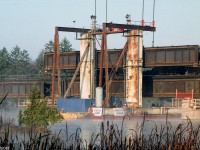 CN was replacing bridge girders over the Trent Canal and River in 1997. Seen here, a Dominion Bridge barge-mounted derrick lifts an old bridge span out onto a heavy-duty flatcar, in preparation of installing a new span in its place.
<br><br>
Photo of a new bridge girder span waiting to be installed, at Belleville ON: <a href=http://www.railpictures.ca/?attachment_id=31955><b>http://www.railpictures.ca/?attachment_id=31955</b></a>