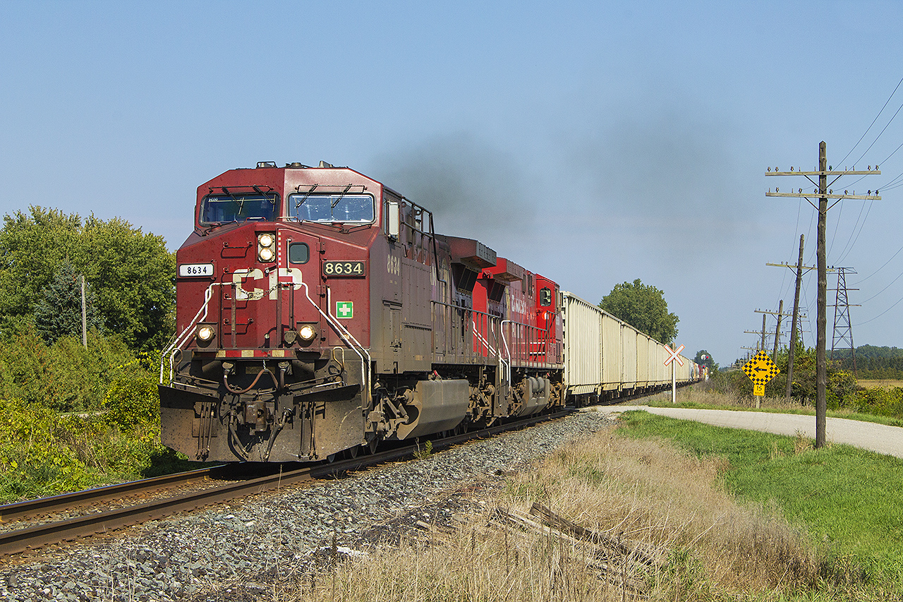 Chasing is always a part of railfanning...especially when you're into photographing trains and all sorts of railway related scenes. This day was no different. Except that a normally 'speedy' freight seemed to have a hard time gaining track speed. Here, with a replacement numberboard 8634 leads 8650 and a long string of gondolas across Third Line. For all of us who can remember, it brings back the 'yester-year' memories of the Alco's and MLW's who usually put on a good smoke show.