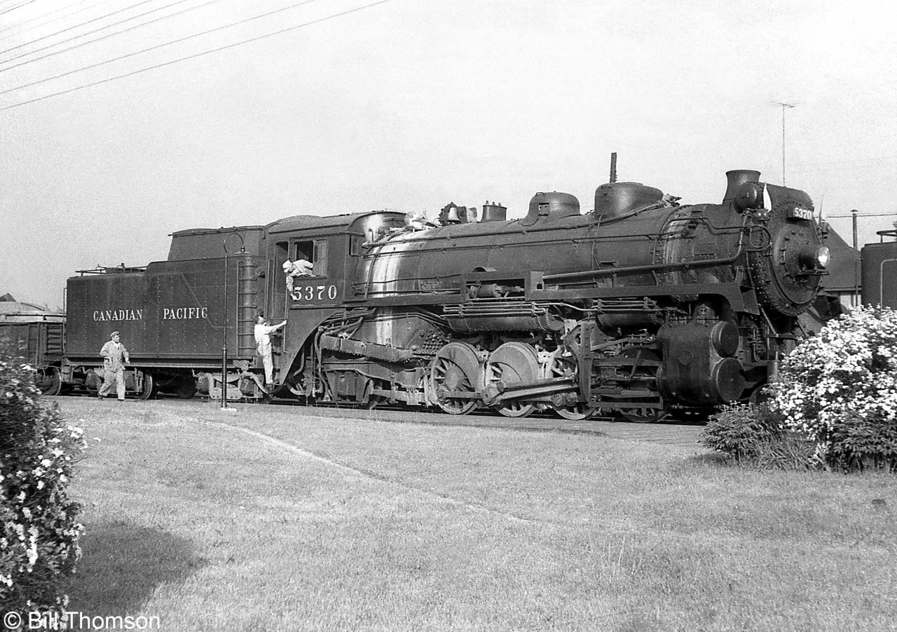 The engine crew of Canadian Pacific P3-class Mikado 5370 sets about their duties during a station stop at Guelph Junction for water. 5370 was the road engine of this westbound freight, with the assist or push engine ahead being G1 Pacific 2228. 

A view of the head end of the train: http://www.railpictures.ca/?attachment_id=25522