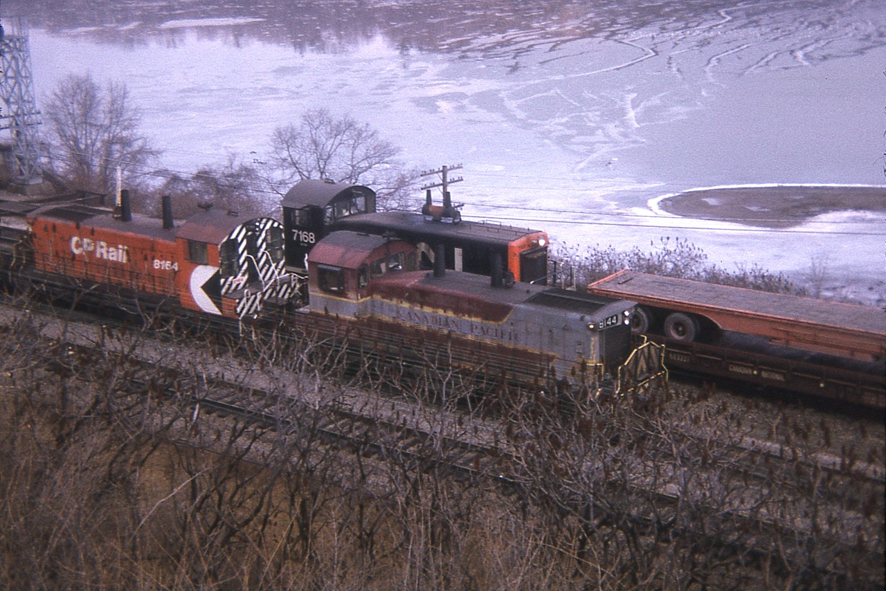 There was no way of getting around that annoying sumac, which was a shame because this was an interesting image with two paint variants of CP being passed by CN just east of the Ham Jct sign. CNs SW8 # 7168 was gone by 1989, whereas the CP SW1200RS units were renumbered, 8144 became 1239 in 1981 and the 8164 became 1251 in 1984. These common switchers,once everywhere it seems, are now almost extinct.