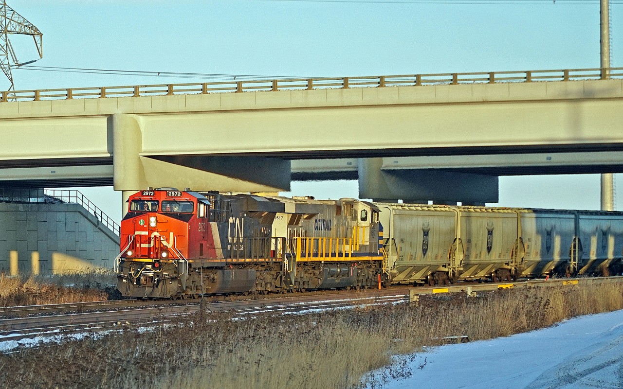 A pair of ES44ACs, CN 2972 and CREX 1517 bring a train of P & H hoppers through Clover Bar.