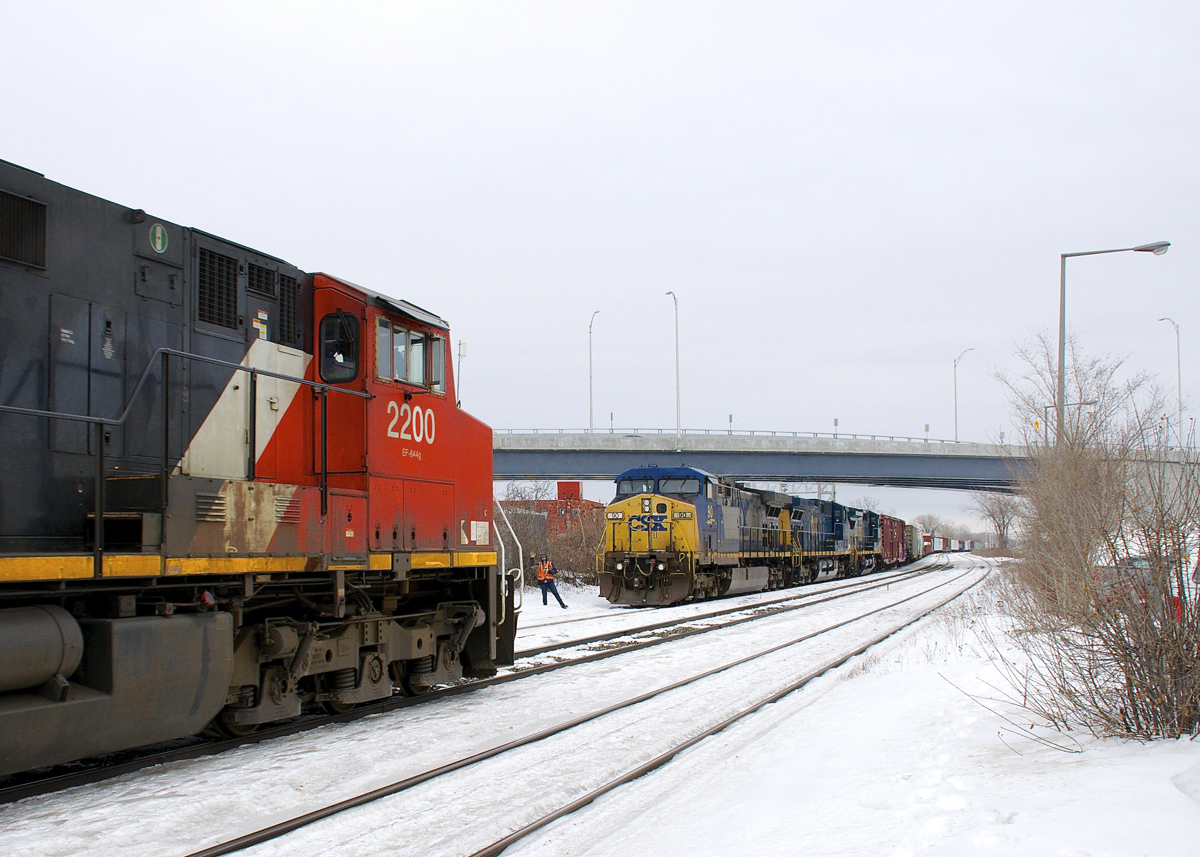 CN 327's crew is out for a roll-by as CN 368 with CN 2200 up front (and CN 8842 mid-train) passes their stopped train where three tracks narrows to two at Dorval. Power on CN 327 is CSXT 90, CSXT 132 & CSXT 7693, with