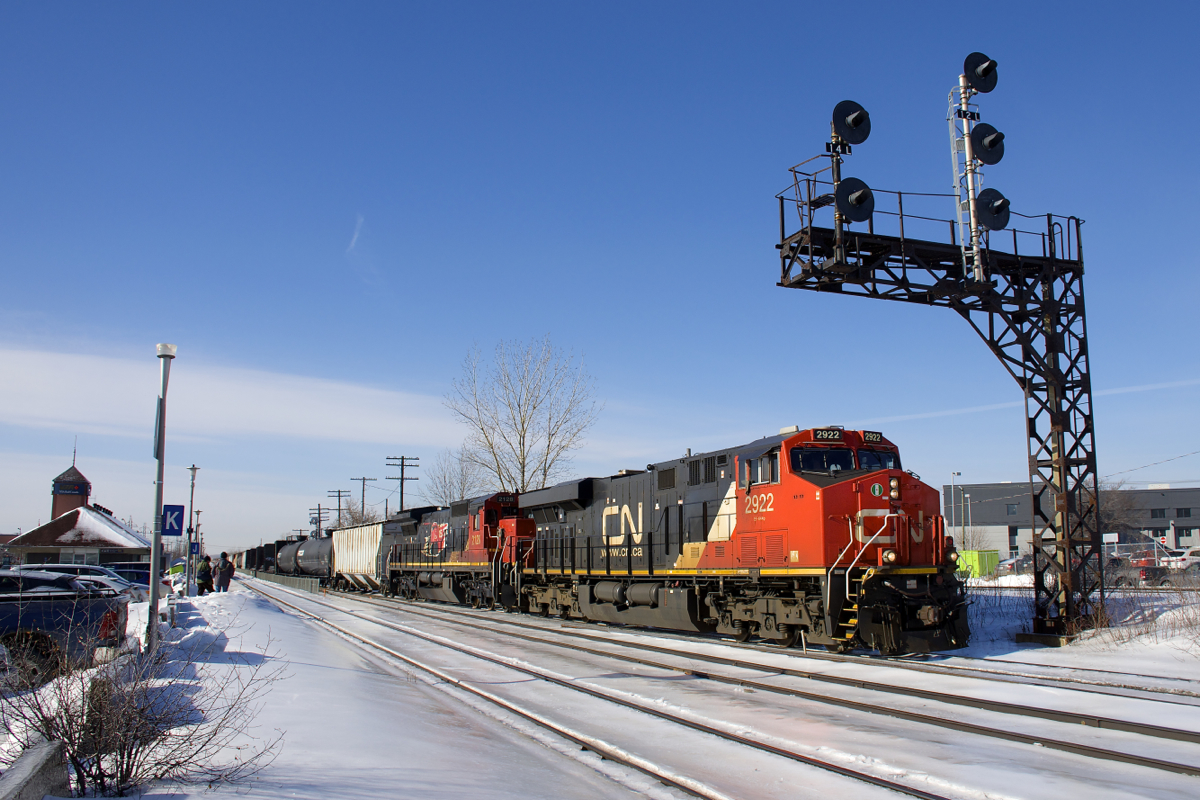 CN 372 has ES44AC CN 2922 (built in 2014) and Dash8-40C CN 2128 (built in 1991) as head end power as it passes under a signal gantry at Dorval as the train crosses from the north track to DX-1 track. Mid-train is CREX 1501, an ES44AC built in 2015. Trailing unit CN 2128 wears a logo commemorating the 15th anniversary of CN's privatization, which took place in 1995.