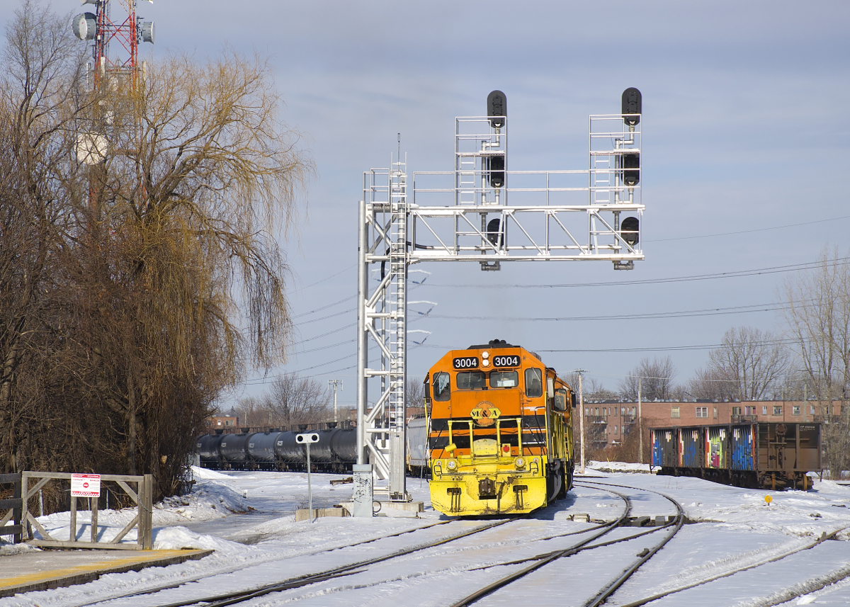 After being stopped at this signal gantry for a short period (waiting for a foreman to clear up ahead), detour SLR 394 is on the move again with SLR 3004 leading four more G&W units as it approaches the platforms at Lasalle Station. At right is the mostly empty Lasalle Yard, with four multimarked hoppers sitting there going back a number of months now. These detour moves have been running every other day up till now, but today light power came up to help empty the backlog of cars in Taschereau Yard, the day after a detour ran.