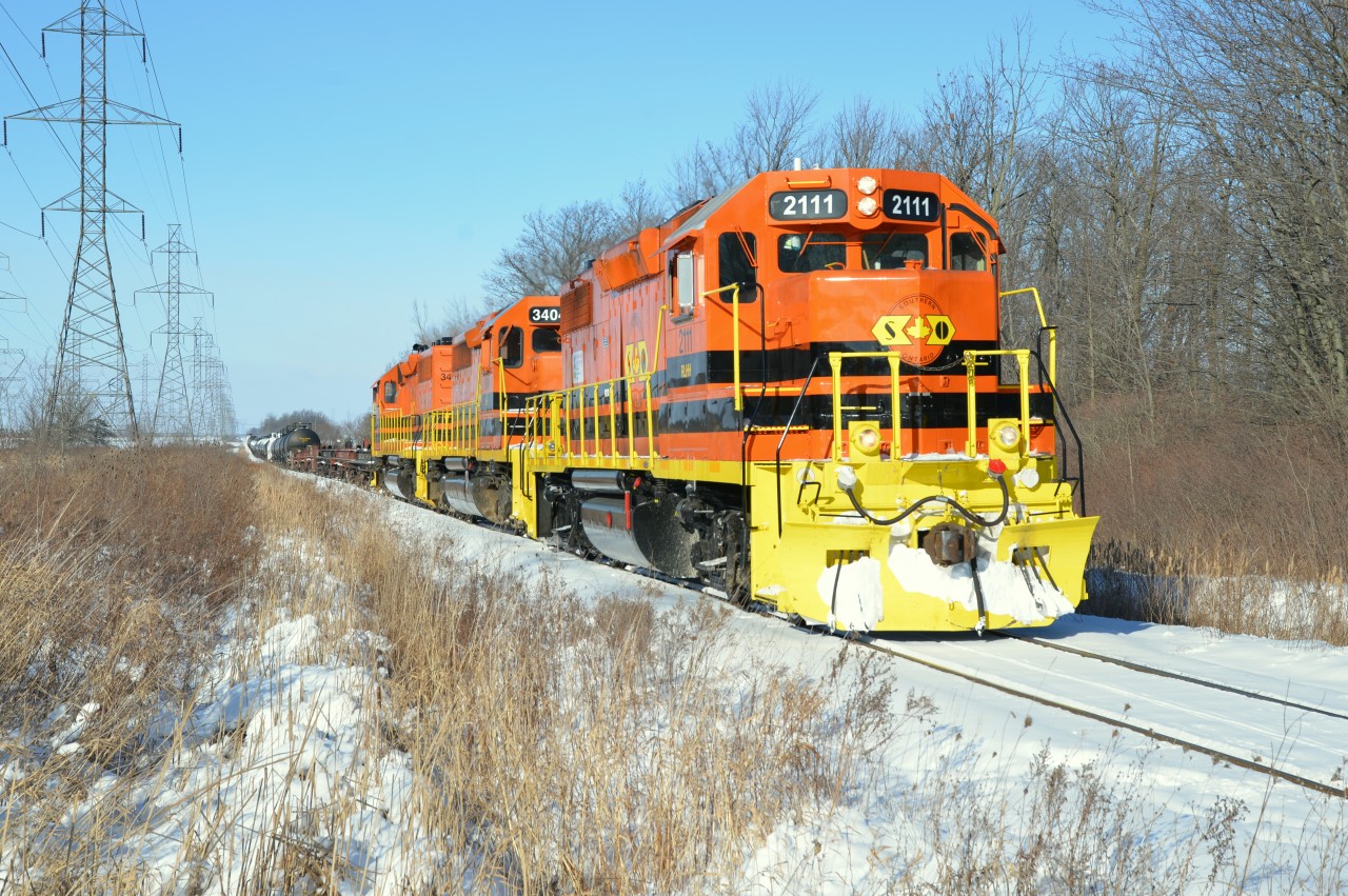 After watching the 129th Rose Parade and spurred on by Honda's leading 3-piece flowered train, I decided to tackle the cold & wind and try for a photo or two of SOR in the Nanticoke area. Good timing as the three freight haulers with a large string of cars were trundling southbound from Garnet Yard. This catch at mp 0.87 represents the first southbound 595 for 2018 and lead by the newest locomotive to visit Walpole RLHH 2111 with stable mates RLHH 3404 and RLHH 3403 trailing. This team will execute a rendezvous with RLHH 2801 at the switch CN Nanticoke prior to heading west on the Stelco Lead with s much shorter string. You gotta feel for the crew in this frigid weather especially the conductor on the ground.