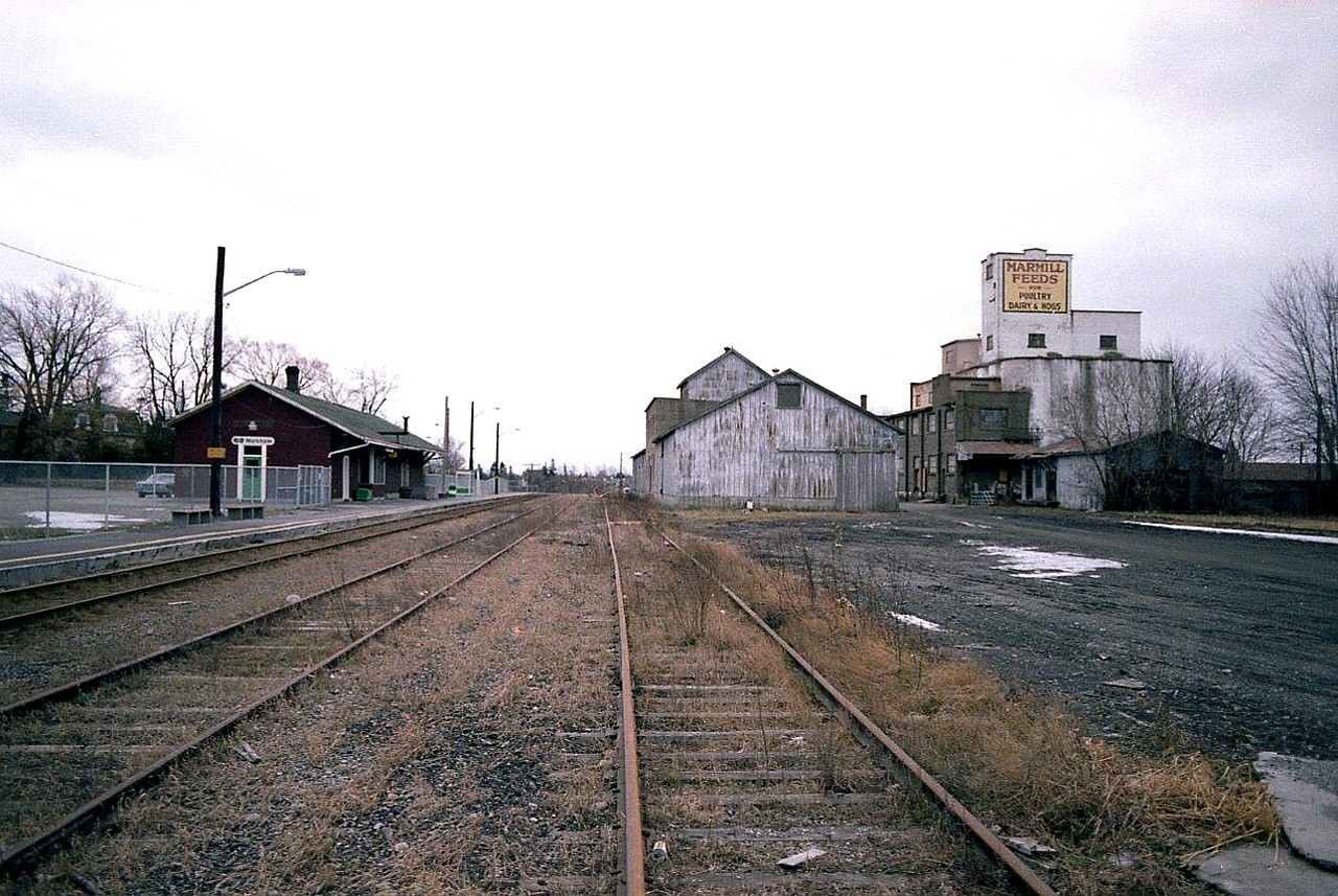 Here is a view looking roughly southward at the old Markham Village station. It is only in it's 4th month as a stop for the GO extension thru here. (Stouffville GO line)  This station was built in 1871 for the Toronto & Nipissing Rwy. Later taken over by GTR and then CNR.Passenger service dried up in the early 1970s. The station was saved from demolition when a millennium project between the City of Markham and the Markham Village Conservatory to purchase the old station and restore it came into being. The station is used for commercial purposes, as GO uses only the platform, not the station itself. It is a Heritage Building. I chose this image, rather than just the station itself, for Railpictures on account all the old structures other than the station are gone, replaced by housing projects and parking for around 250 cars. This scene is so rural in appearance compared to the present day.