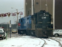 Back in the days when it was the Conrail Mainline thru Niagara Falls, we see two CR units having just entered the CR-CN connector which went over to the CN yard in town. This is a 'going away' shot, with CR 5823 leading 7433, about to cross thru the intersection of Queen and Erie Sts.  That is Rosberg Dept store on the right, still in business and sporting holiday decorations. In the far background left and centre is the Bridge St. VIA station. The power will head over to the CN, and then bring some traffic back to CR Montrose at the south end of the city. Quite the old time lights on the cop car.