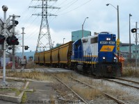 There's prototype for everything. Witness this strange move: SOR Conductor Lance Brown eases cut of unpainted steel hoppers across Beach Ave in Hamilton. These cars were lifted from National Steel Car to be put into storage on the former Stelco Bar Mill's tracks in Hamilton's industrial basin which were used for car storage at the time. NSC was a busy place and within a few weeks (or months) these cars were sent in for painting and shipped out.<br><Br>Lots of details here also - notice the white (flashing) signal? These were installed by the TH&B as this lead  is used for CP for the TH&B (now CP) Adams yard and these flashing signals are found on most of the CP/TH&B Maintained crossing signals in the area. The track in foreground is the former CN Ore Train lead - Dofasco ore trains would have reversed (heading behind the photographer) to Dofasco to unload ore and making the reverse move back through here, to the Lysaught lead (wye by Dofasco Central Shipping in distance) back onto the Grimsby sub at Parkdale yard destined for  the Newmarket sub and the Sherman Mine on the ONR for reloading. The Ore train lead also hosted Dofasco engine movements until 2012 or so once or twice a week - now ended. In the far distance there was a fourth track crossing as part of this circuit - which was a Dofasco only track for internal switching moves - remnants exist but it was a long time ago that you had Dofasco, CN and CP tracks  with  switchers crossing here dozens of times a day. In contemporary times you can find SOR and CP here a few times a day as it's basically all joint track (both railways retain access) - don't hesitate to visit here when fishing for locals in Hamilton, your chances are usually pretty good.