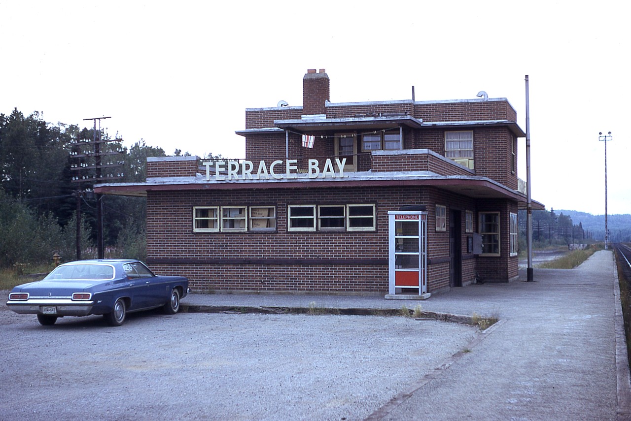 This rather modern CP station, built in 1951, replaced another that was built in 1947 and was flooded out. The station was at the east end of what was called 'Black Siding', which ran parallel to the mainline thru Terrace Bay. A yard was constructed later here, to service the Longlac Pulp & Paper Co that started up just off the main, and was connected by a service track off the main near the station. The railroad was rather busy back then, with freight and passenger service alike until a highway connection finally reached the town in 1960.
Note the agent's living quarters upstairs, a common practice thru the northern towns, in this image accentuated by the laundry hanging  outside.  Do not have a demolition date for this rather solid looking structure, but it has been gone for a number of years since I shot this in 1975.