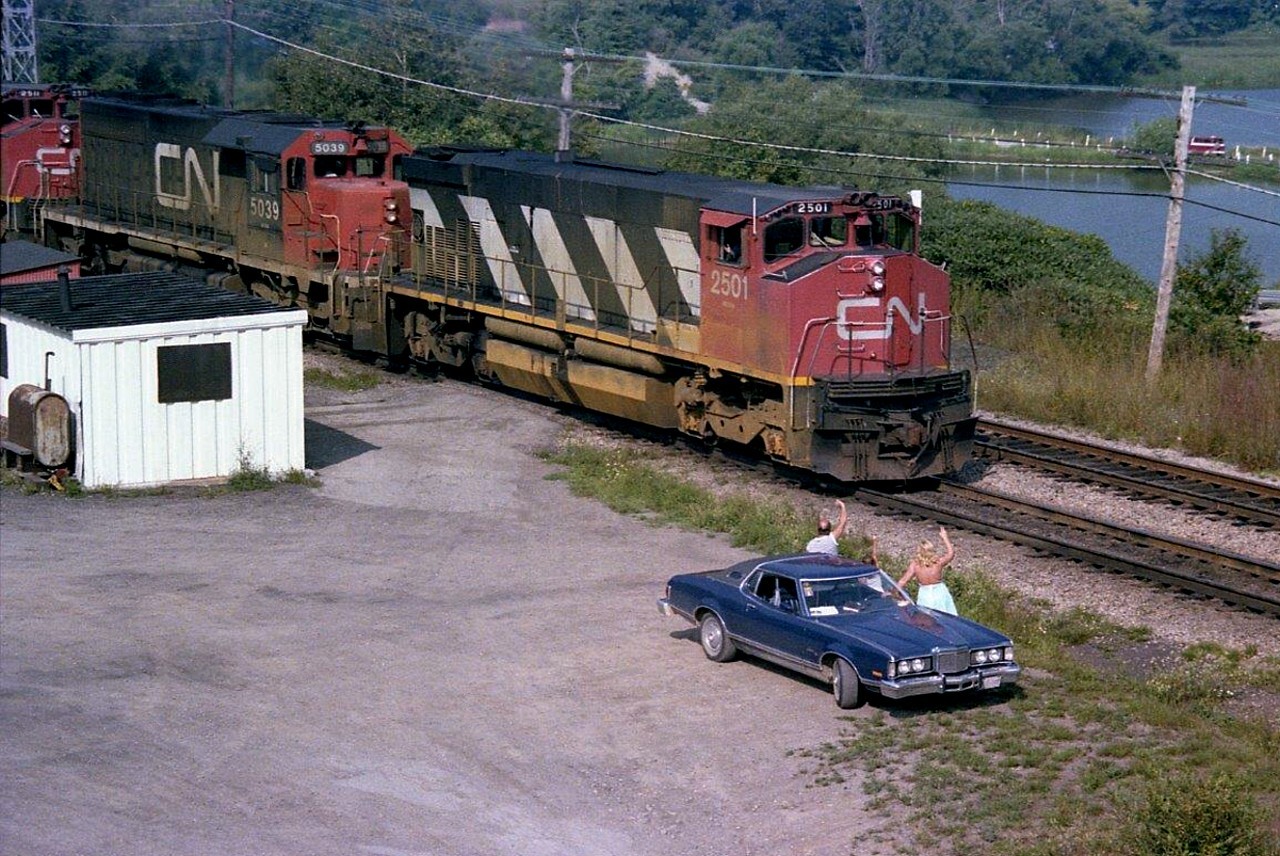It is the afternoon "Pulp Train", as we used to call #333, and today it had CN 2501, 5039 and 2511 on the head end. There to greet it is Graham Robertson (or Robinson, I forget) his daughter as well as my old sidekick Laurel. Thats the old '76 Cougar, a car I had 19 years taking up the rest of the scene. Nice that the engineer acknowledges the waves.  Train triple three left Mac Yd daily and made its way to Port Robinson, where it left cars of logs for the Ontario Pulp and Paper at Thorold South, before continuing on to the US of A. I have often wondered where Graham ended up. Not seen him in many years.