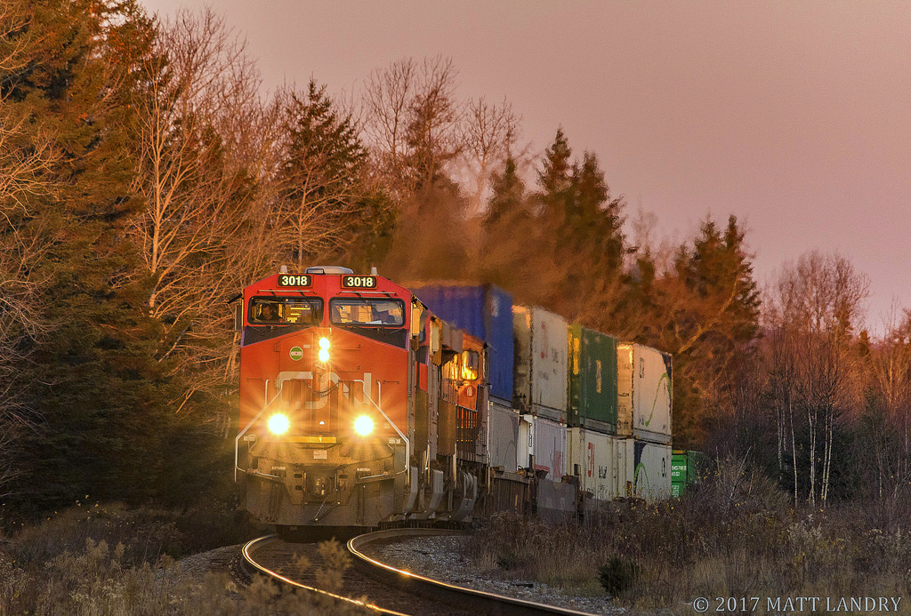 CN 3018 leads stack train Q120, as they head into the sun at East Mines, approaching Debert, Nova Scotia.