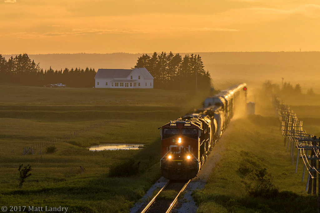 With the sun nearly set for another summer day, casting a great yellow glow, eastbound train 408 heads by Fort Lawrence, as they approach Amherst, Nova Scotia.