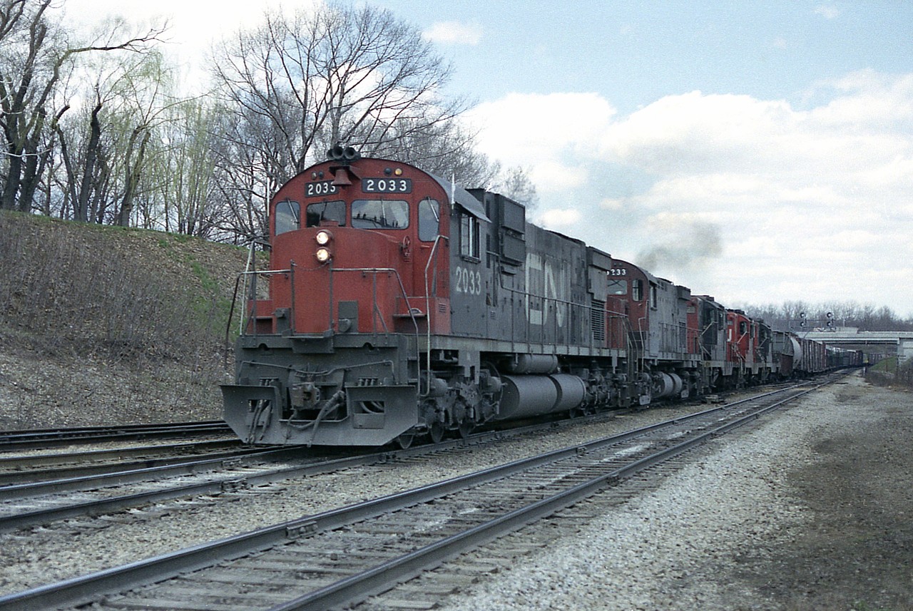 Trust the high sun to nip behind a couple of ugly clouds to try and spoil such a nice set of power. CN 2033, 3233, 4529, 4567 and 4563 are Fort Erie bound with 82 cars and van #79454 in tow, according to my notes. The image was snapped jut before the train entered the junction itself. The second unit is an MLW C-424, of which I saw very few of even back then.