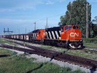 CN M420W 3560 and GP9 4318 lead a ballast train through St. Lambert on a beautiful summer evening in July 1990.