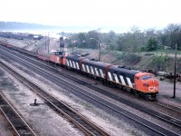 By 1986, many of CN's F7u locomotives had been displaced from service in Western Canada and migrated east. Most held assignments in southern Ontario, such as the Hamilton-Nanticoke "steel train" which regularly used an A-B-A set. Here we see 725 leaving Hamilton Yard and about to head up the Escarpment via street-running on Ferguson Avenue. The train carried two cabooses/vans to facilitate run-around moves in Nanticoke and Brantford.