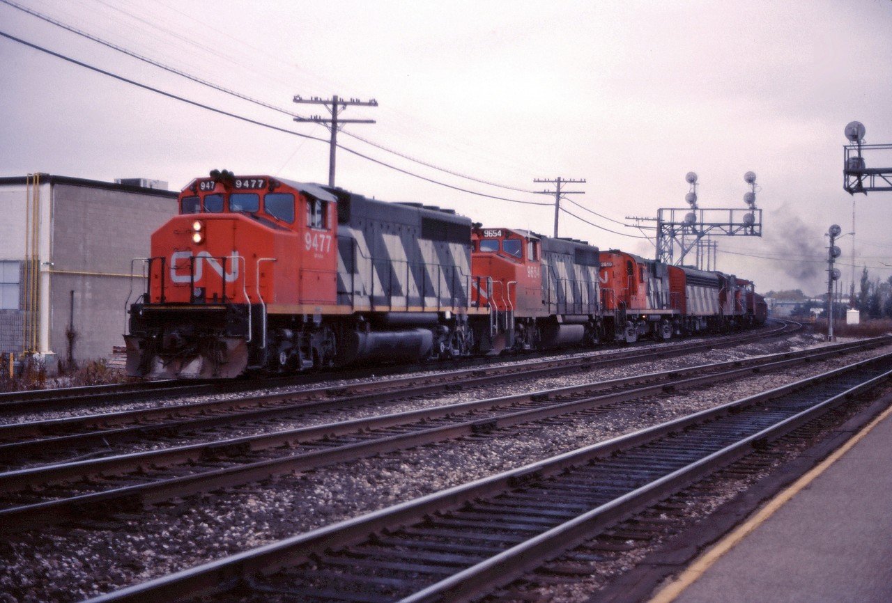 CN GP40-2LWs 9477 and 9654, lead RS18 3619, an F7Bu, a GP9 and an SW1200RS westbound through Burlington in an undated mid-1980s photo.