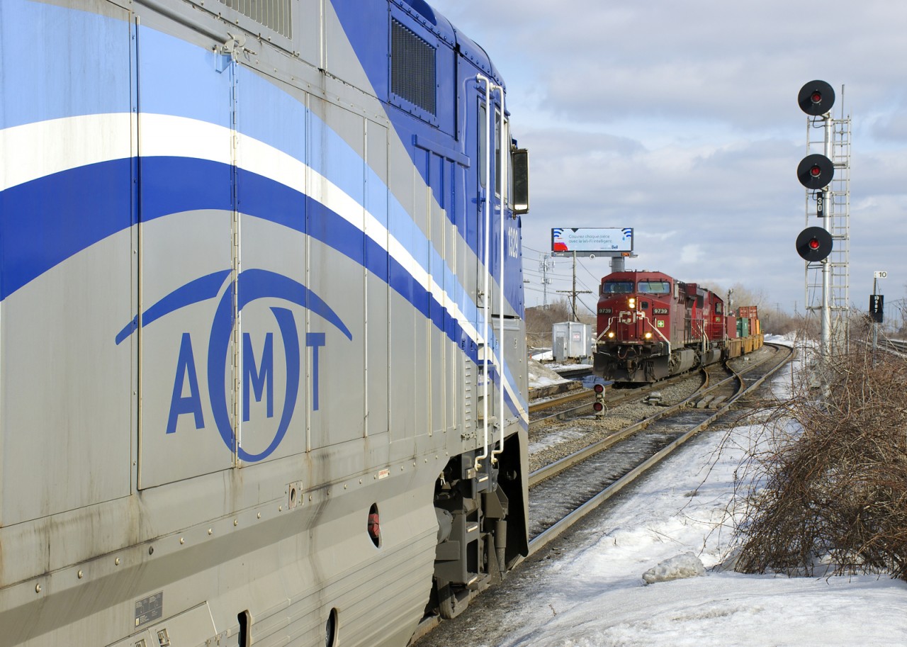 AMT 1329 and CP 9739 face off as a westbound commuter train with the F59PHI pushing makes its stop at Lachine Station and CP 143 with CP 9739 leading slowly approaches the station while lifting out of St-Luc Yard.