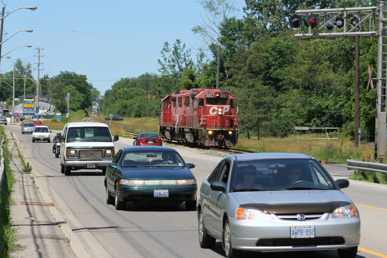 Light power, Canadian Pacific GP38-2’s 3057 and 3038, both still in their duel flags paint scheme, are seen returning to Galt, Ontario as they trundle along beside busy King Street East in Kitchener on the Waterloo Subdivision. The crew has just set-off traffic with the Goderich-Exeter Railway (GEXR) at Kitchener at the interchange between the two companies.