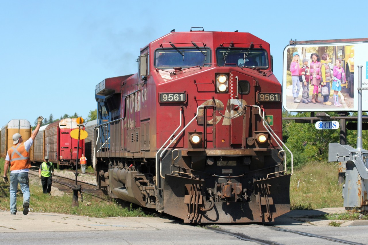 With a friendly wave from a fellow crew member, an eastbound Canadian Pacific train begins to accelerate over the Hespeler Road crossing in Cambridge, Ontario on the Waterloo Subdivision. CP AC4400CW 9561 and leased CEFX AC4400CW 1042 would eventually bring a cut of newly loaded auto racks to their awaiting main line train at Galt, before heading east to Toronto.