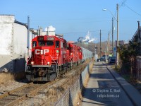 In the alleyway's of Hamilton's North End, Dofasco looms large in the background. A Yard job from Kinnear is pulling up grade to lift their train out of the dip caused by the CNR Grimsby Subdivision underpass which was built in 1900 during construction of this, the TH&B Belt Line. The Belt Line was constructed across an already developed and burgeoning city and as a result, comes very close to homes and businesses and cuts across numerous major thoroughfares<br><br>After a photograph of the <a href=http://www.railpictures.ca/?attachment_id=32110 target=_blank>SOR Earlier this morning</a> and with my free time running out I scoped out a shot on the Belt Line as the light would be really nice heading back to Kinnear - this scene peaked my interest and I lucked out - sometimes CP will lift NSC, set off most of their traffic in Adams Yard and come back with next to nothing. But this day, they doubled onto a lift at NSC which stretched them from Kenilworth to nearly Ottawa St then took off for Kinnear giving me a nice long train at this location. Included in this mix were some BNSF well cars on the tail end. This was my final photo of the morning and I went straight for home with plans in the afternoon.