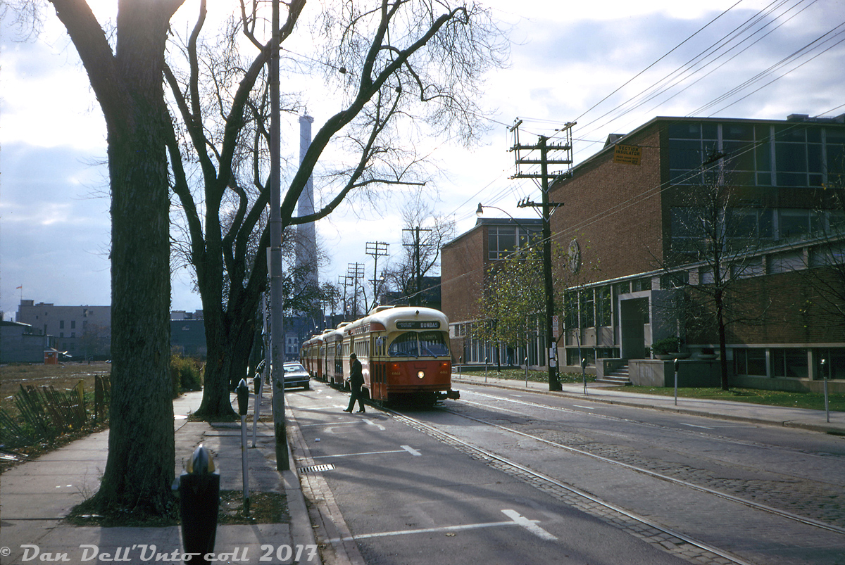 In this late morning/early afternoon Fall shot, four TTC PCC streetcars lead by 4466 line up on McCaul Street just south of Dundas Street, next to the old Ontario College of Art building (today OCAD University, with this building heavily artified, er, modified) looking south to Queen St. in the distance. Due to disruption by the annual Eatons Santa Claus Parade, the streetcars have been staged on McCaul for entering service as "Gap Filler" cars, a regular annual practice. The large object that looks like a smokestack in the background is just the iconic CN Tower under construction.

Original photographer unknown, slide from the Dan Dell'Unto collection.