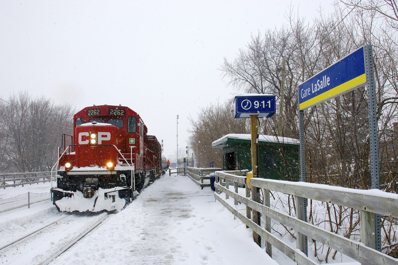 After setting off two transformers in Lasalle Yard, a CP switcher is leaving the yard as it passes Lasalle Station. Soon it will back up to nearby St-Luc Yard with CP 2262 pushing two buffer cars; a crewmember can be seen hanging onto the last car.