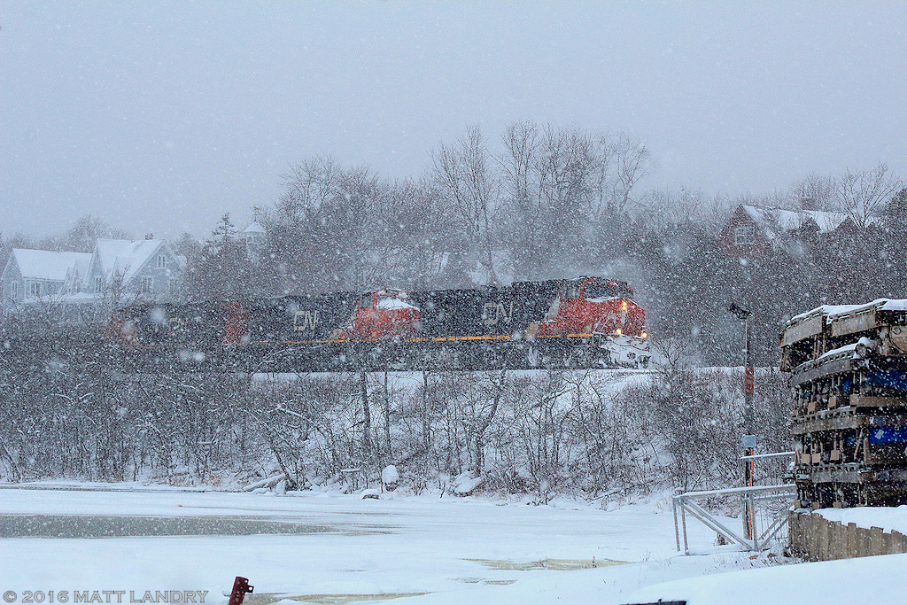 During a snow squall, CN train 406 rumbles along the Kennebacasis River, as they head by the Rothesay Yacht Club, approaching Saint John, New Brunswick.